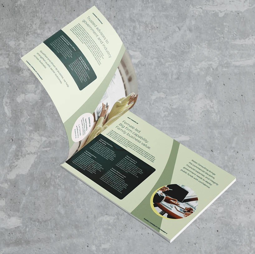 An open brochure made from 90% recycled materials lies on a gray concrete surface, displaying sections of text, charts, and images of hands holding plants and people using a laptop, with a green and cream-colored design theme.